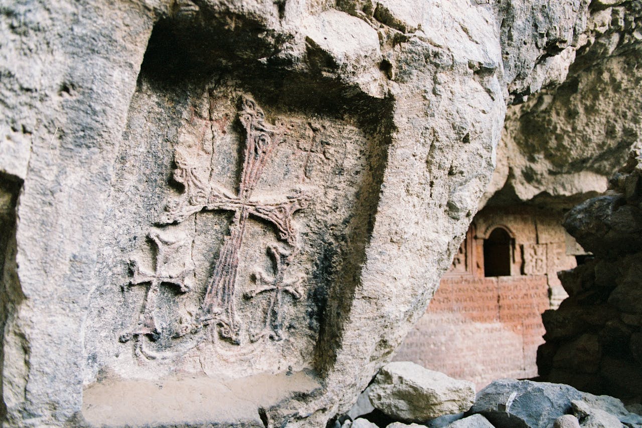 Detailed view of a carved stone cross on an ancient rock wall, showcasing historical art.