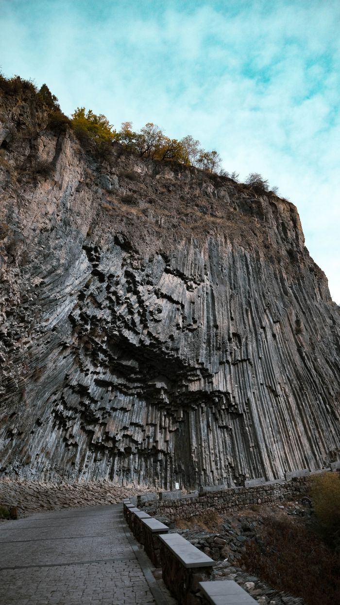 gallery-6 Stunning vertical columnar basalt formation with a paved road foreground, ideal for geology exploration.