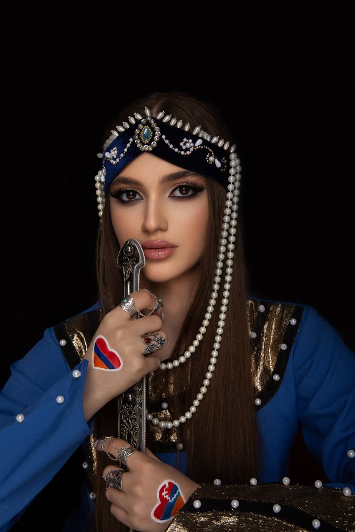 why-choose-us Portrait of an Armenian woman in traditional attire, adorned with jewelry and holding a sword.