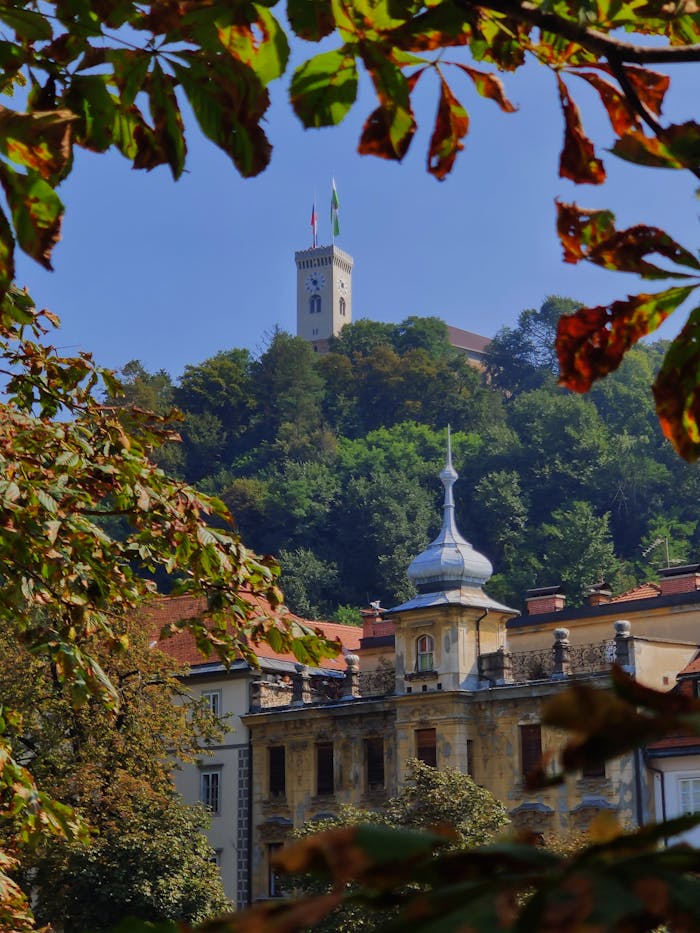 Ljubljana Castle on a hill, framed by autumn leaves, showcasing Slovenia's architectural beauty.