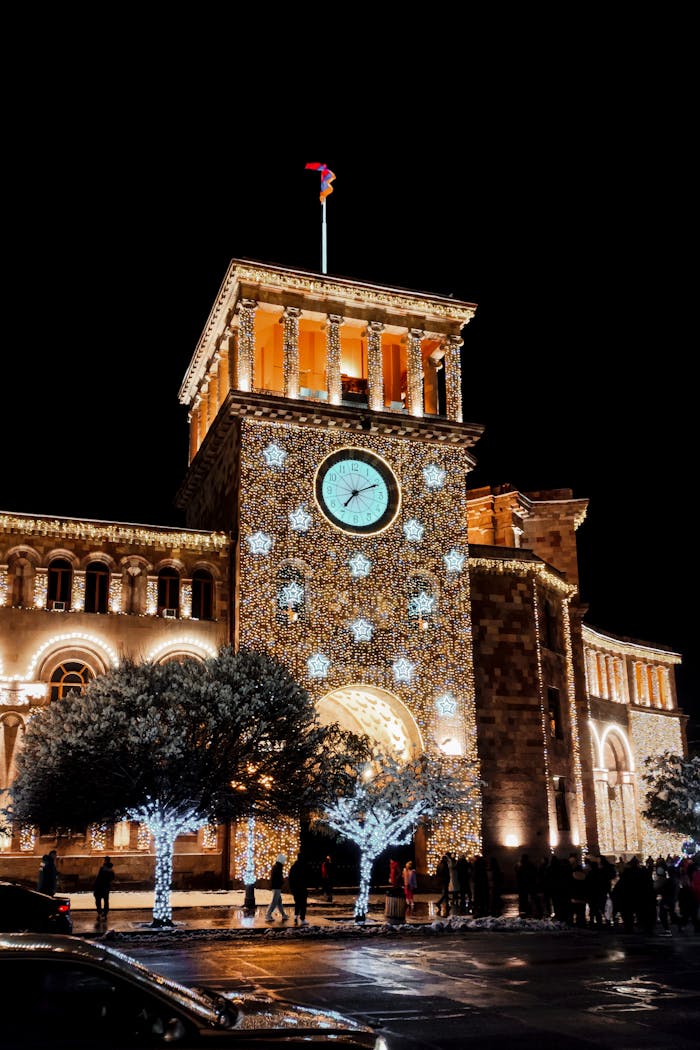 about-01 Festive night scene featuring the illuminated clock tower in Yerevan, Armenia with Christmas decorations.